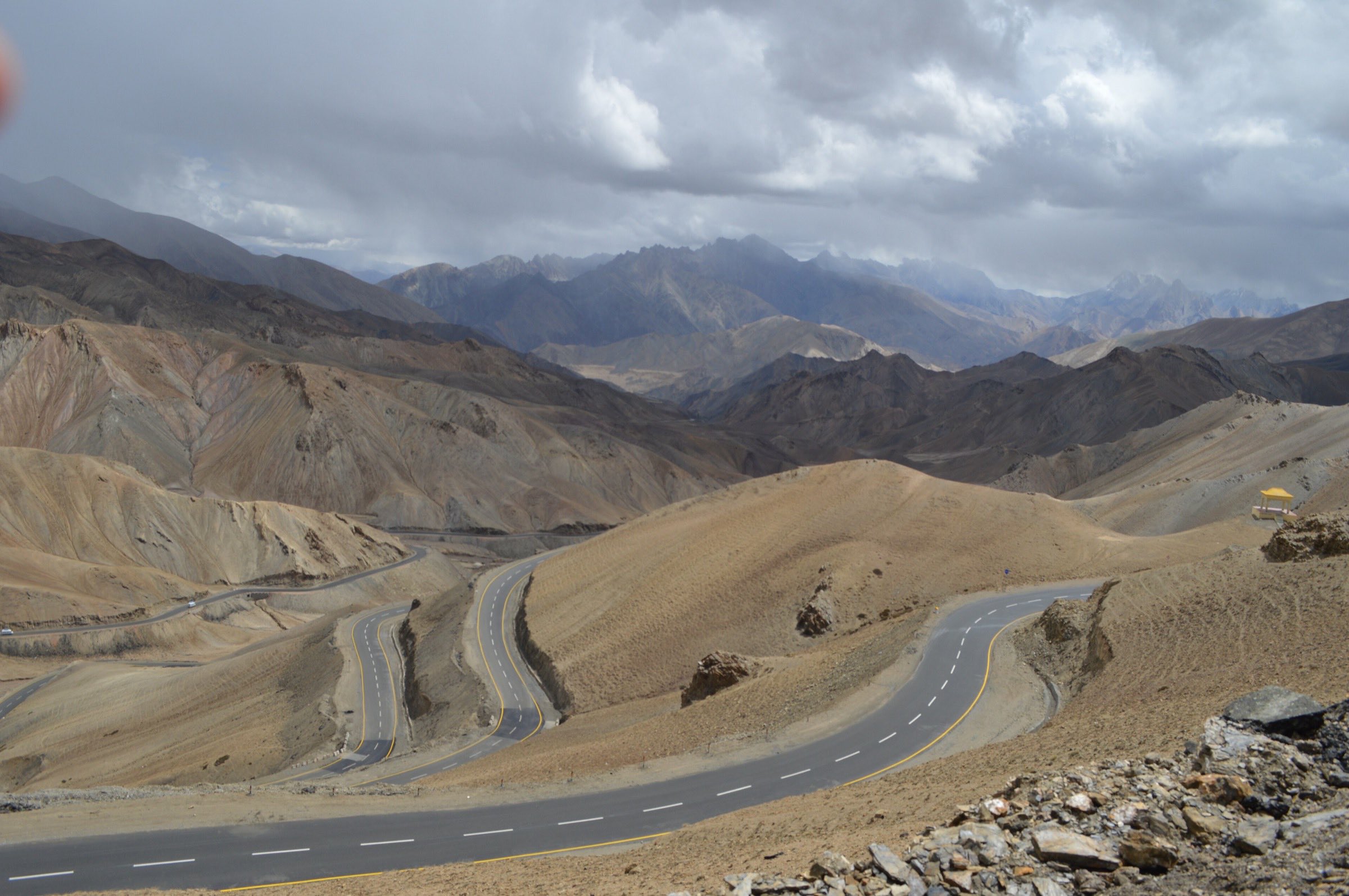 A wide mountain highway in northern India, sweeping through arid ridges.